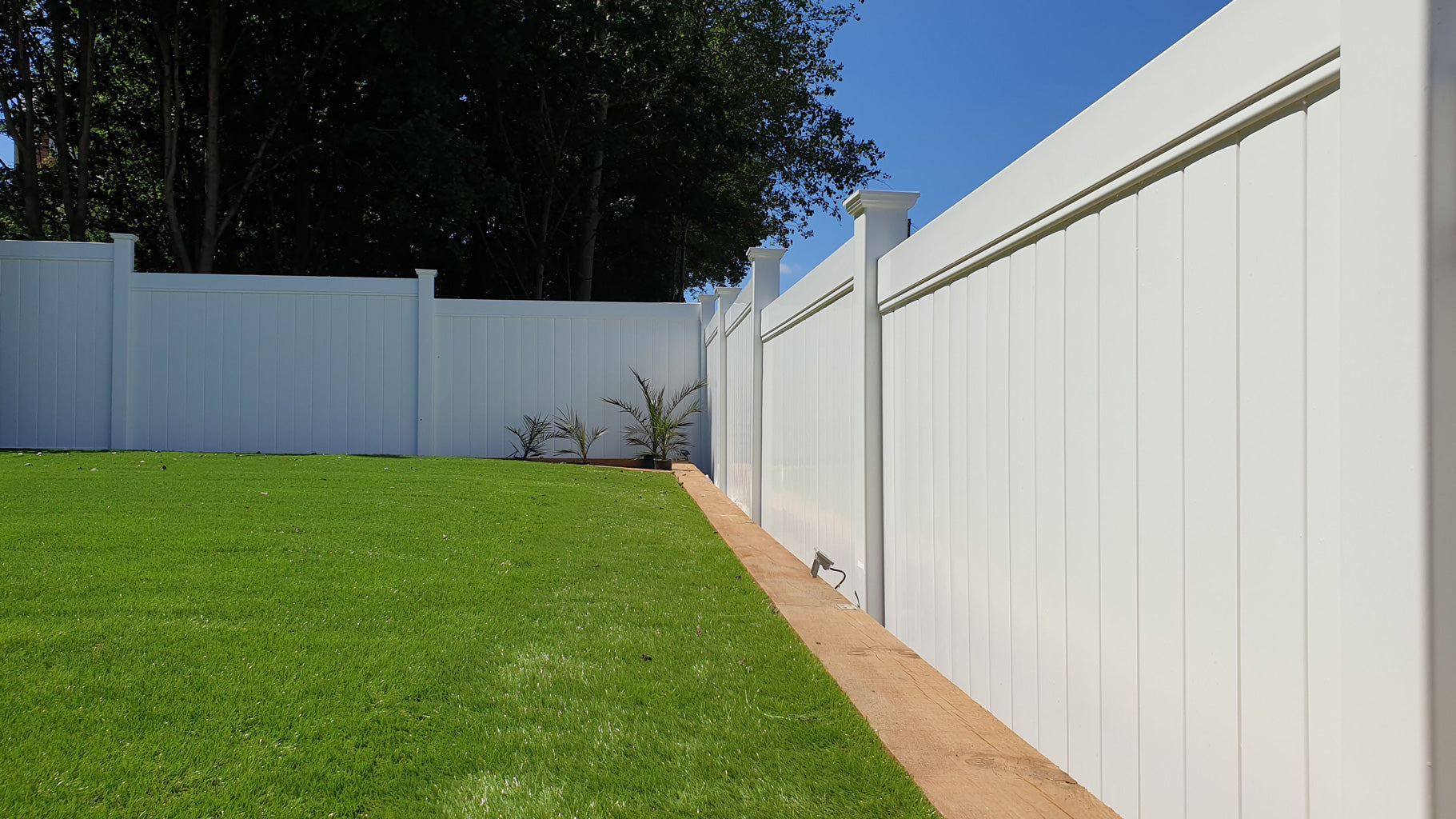 Cascade tongue and groove privacy fence panel, 8ft x 6ft, white vinyl fencing in a garden setting with green grass and blue sky.