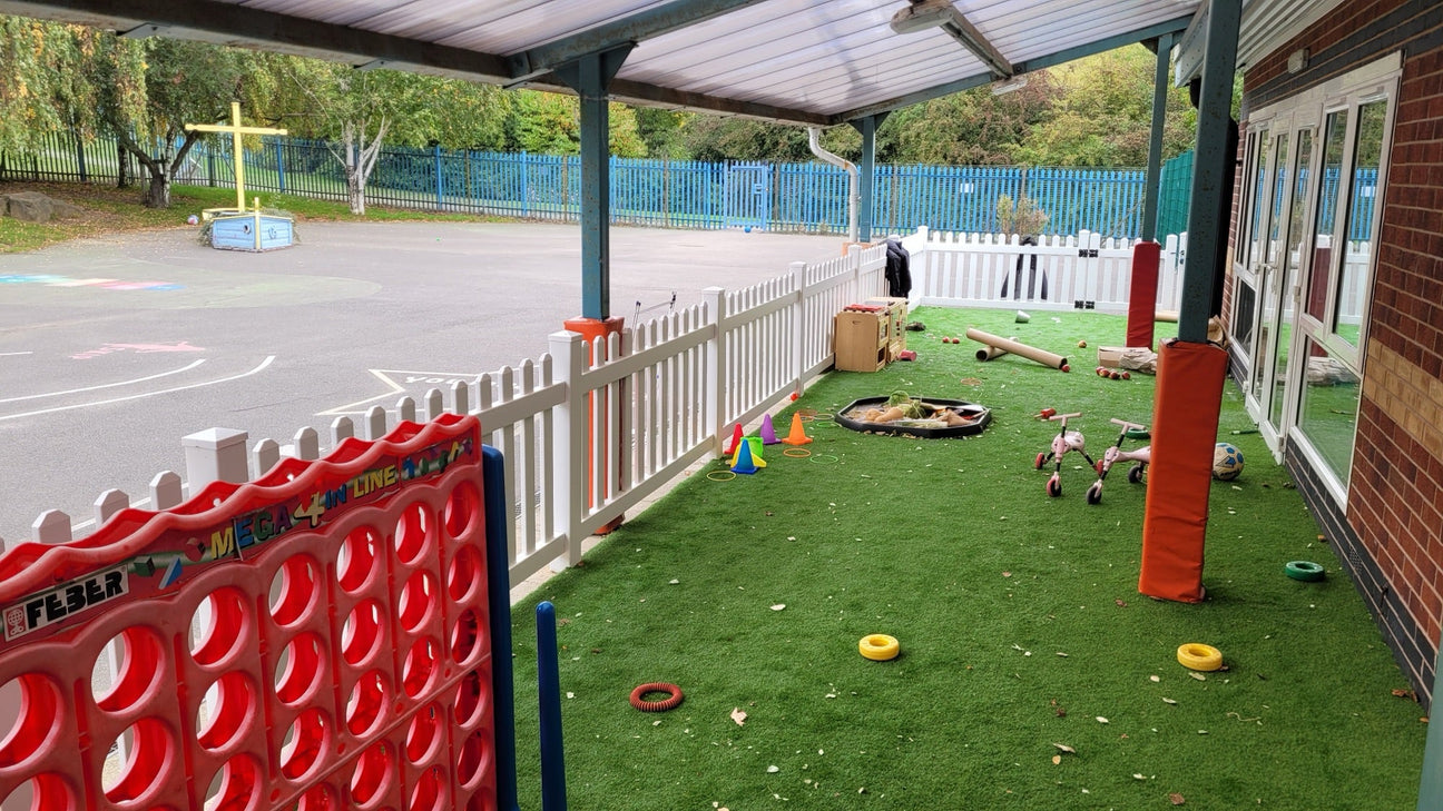 White PVC picket fencing around a nursery outdoor play area under a canopy