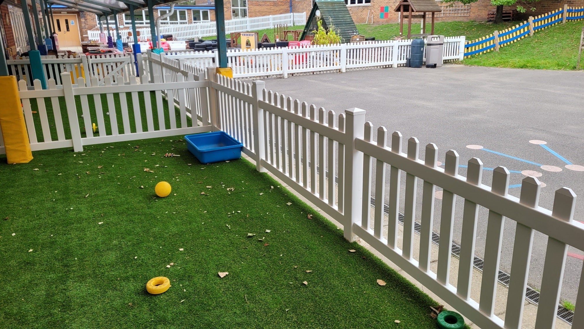 White PVC picket fence enclosing a play area, turning a corner