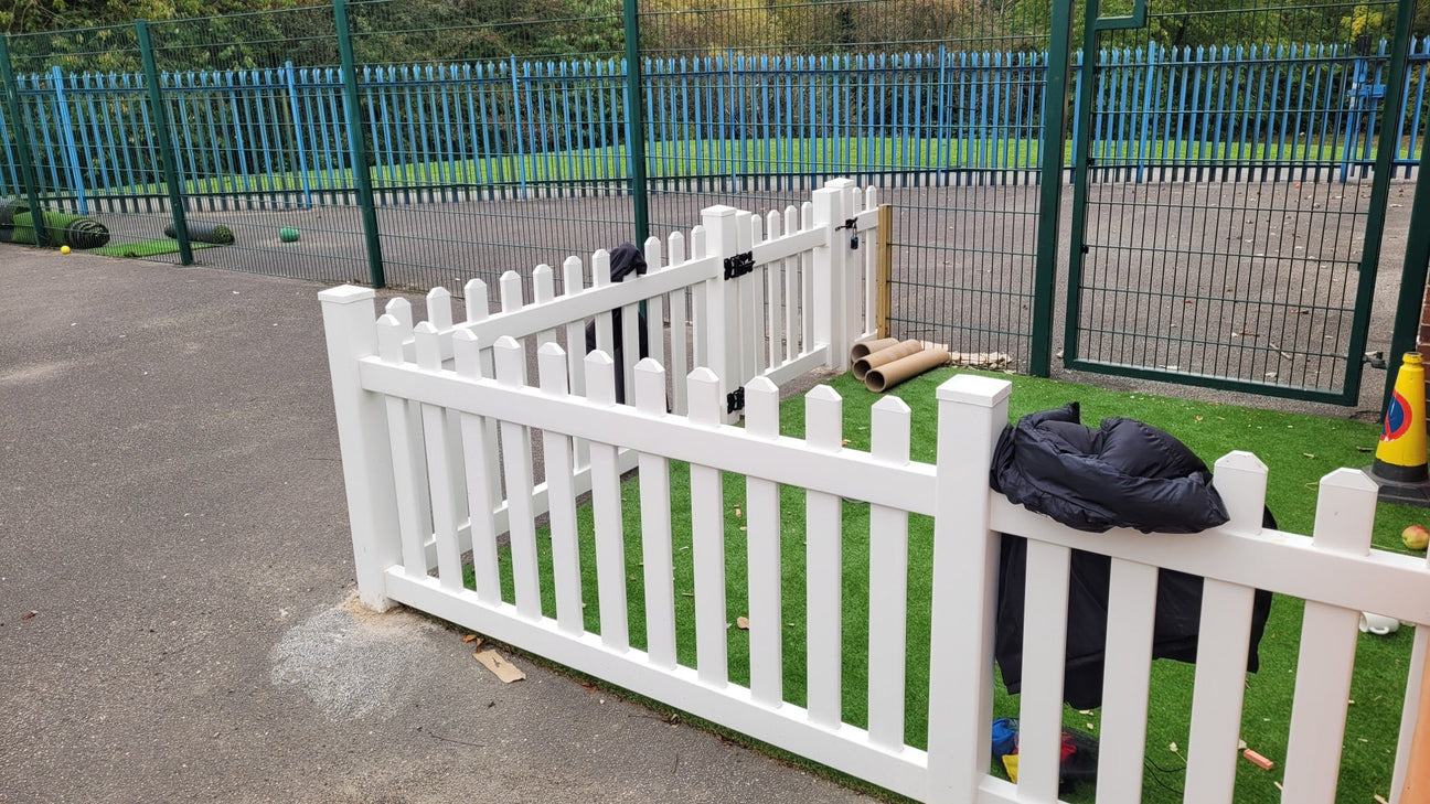 White PVC gate with self-closing hinges fitted at a play area