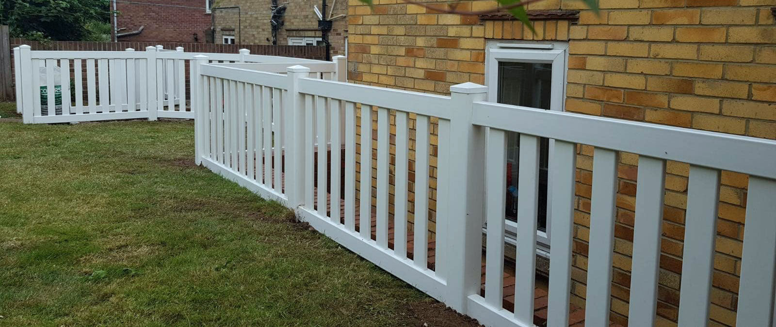 A durable white PVC Flat Baluster Pool Gate by Simple Fencing, providing a stylish and secure safety barrier for a swimming pool area.
