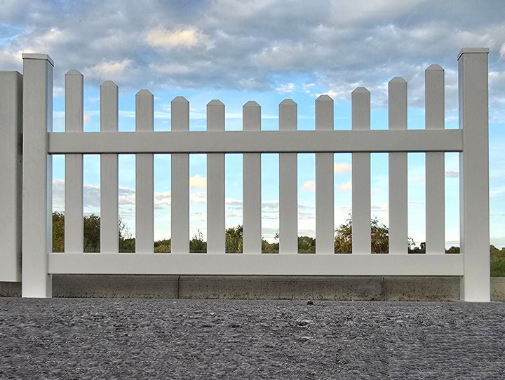 White picket fence with a blue sky and clouds in the background