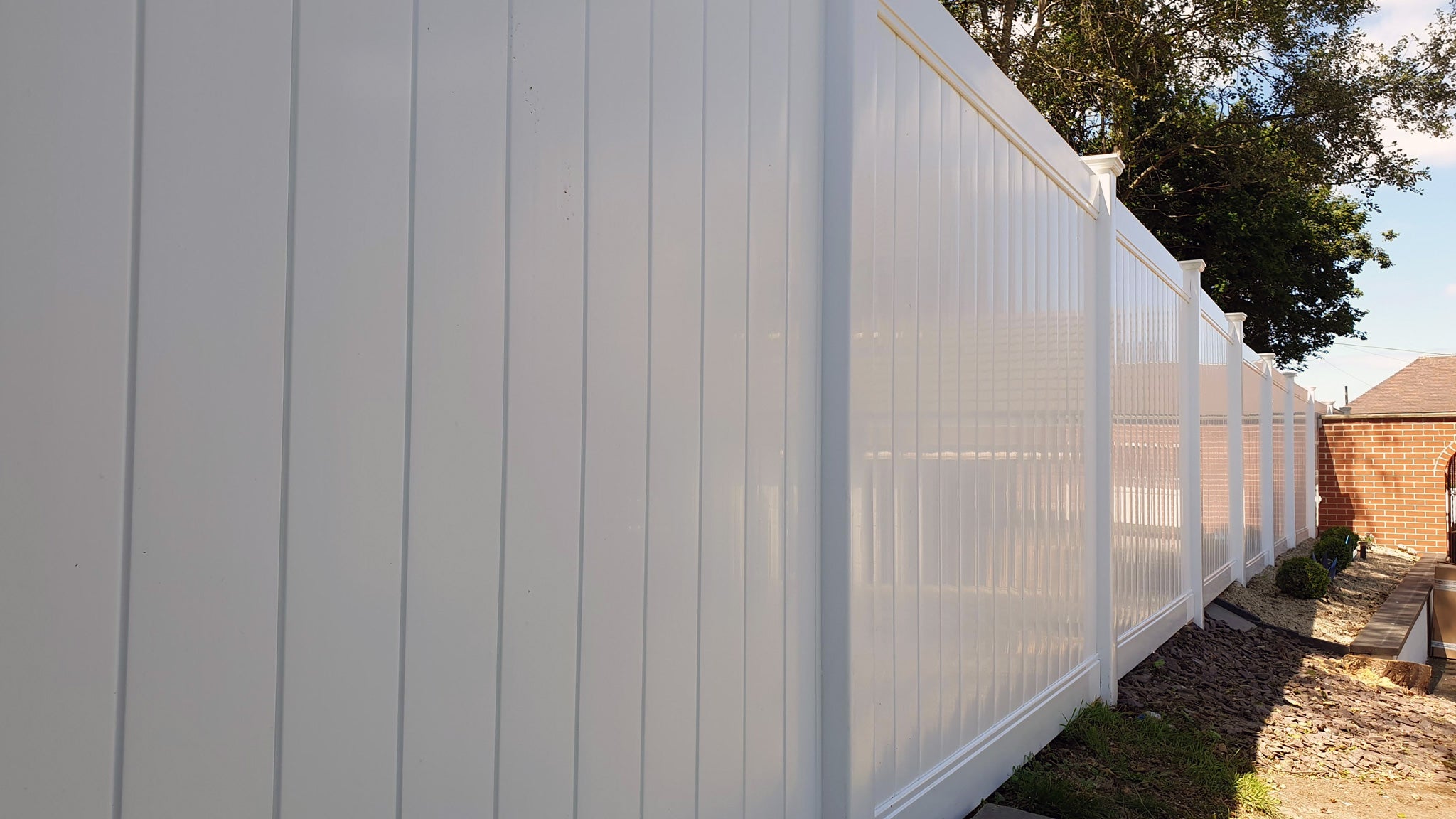 White vinyl privacy fence with a clear sky background